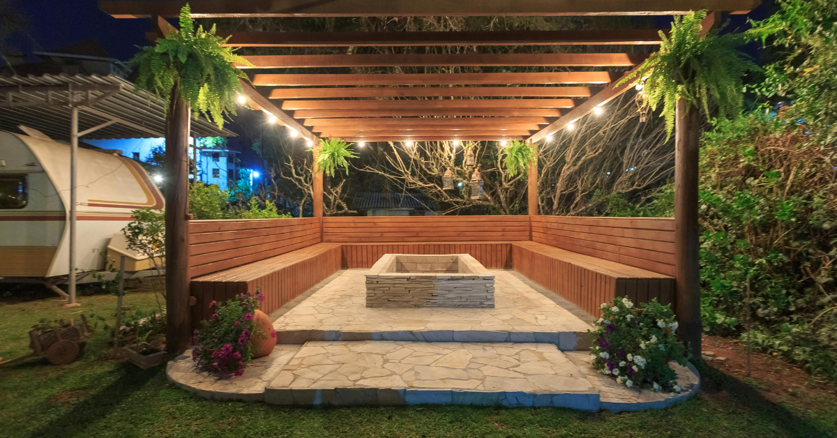 Illuminated blue lanterns hang under a pergola at dusk, creating a warm, inviting ambiance.